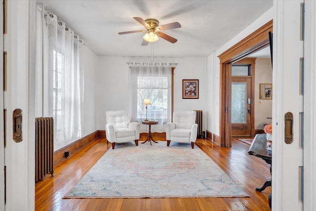 living area with light hardwood / wood-style flooring, radiator heating unit, and ceiling fan