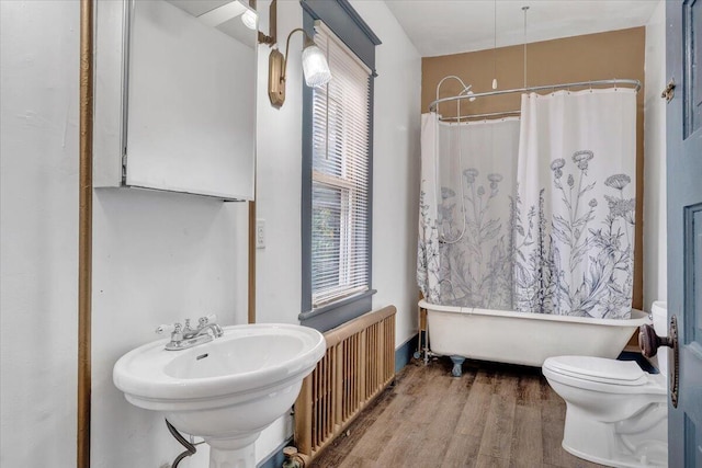 full bathroom featuring toilet, wood-type flooring, sink, shower / tub combo with curtain, and radiator heating unit