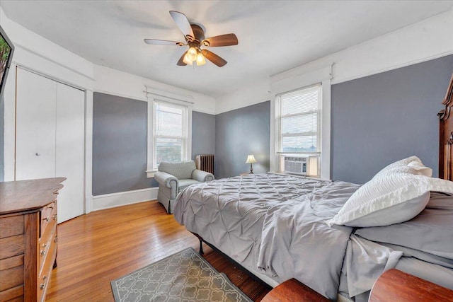 bedroom featuring radiator, ceiling fan, multiple windows, and light wood-type flooring