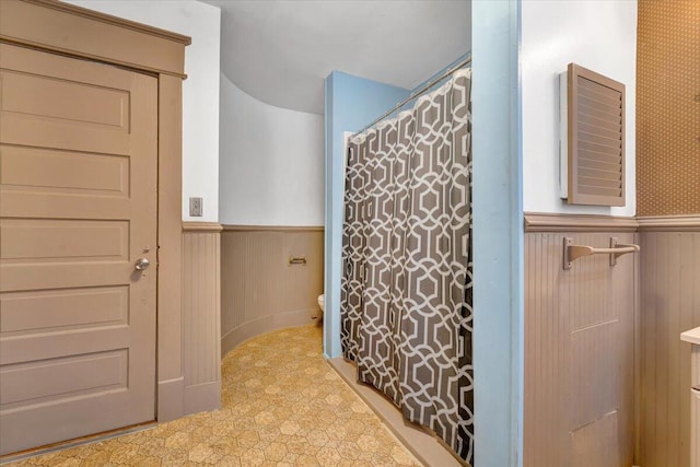 bathroom with toilet and wood walls