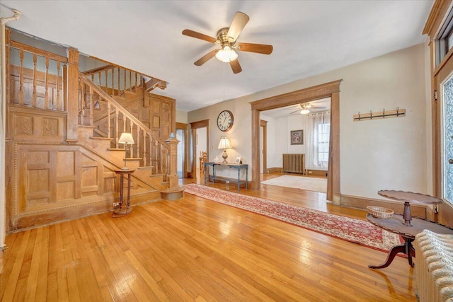 unfurnished living room featuring radiator, ceiling fan, and wood-type flooring