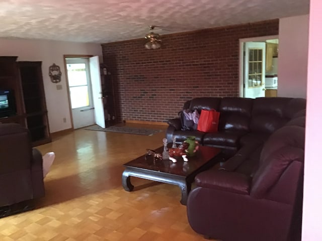 living room with brick wall, a textured ceiling, and ceiling fan