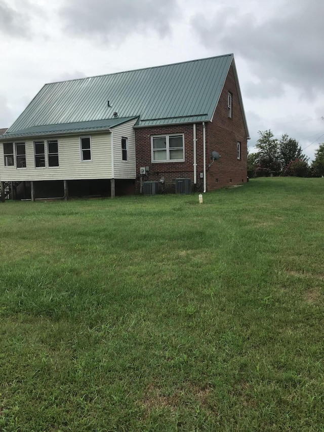 back of property featuring central AC and a lawn