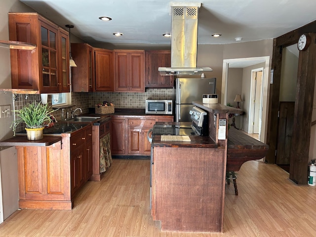 kitchen featuring a breakfast bar, stainless steel appliances, island exhaust hood, light hardwood / wood-style floors, and a kitchen island