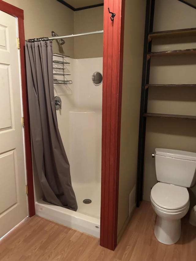 bathroom with hardwood / wood-style flooring, toilet, and walk in shower