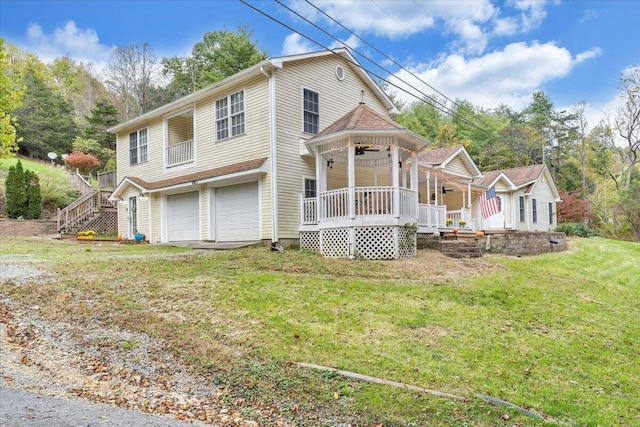 view of front facade with a garage, a front lawn, ceiling fan, and a porch