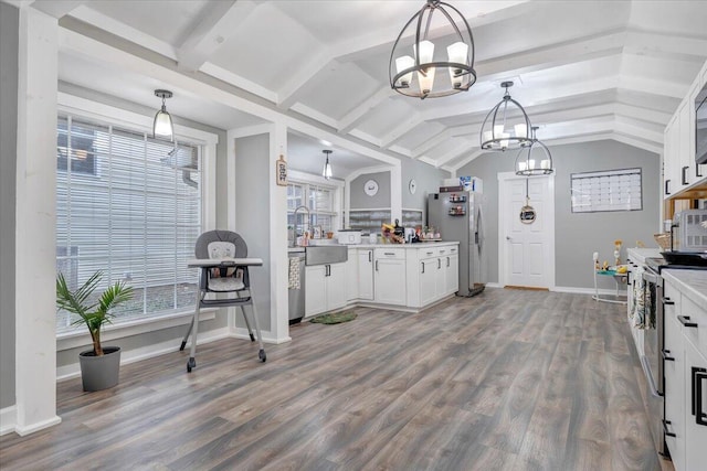 kitchen with white cabinetry, wood-type flooring, decorative light fixtures, vaulted ceiling, and stainless steel appliances