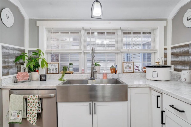 kitchen with sink, light stone counters, decorative light fixtures, dishwasher, and white cabinets