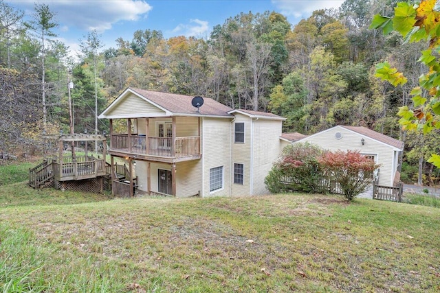 rear view of property with a wooden deck and a lawn