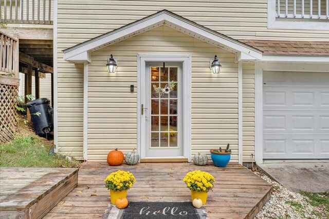 view of exterior entry with a wooden deck and a garage