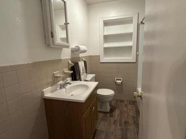 bathroom with hardwood / wood-style flooring, vanity, toilet, and tile walls