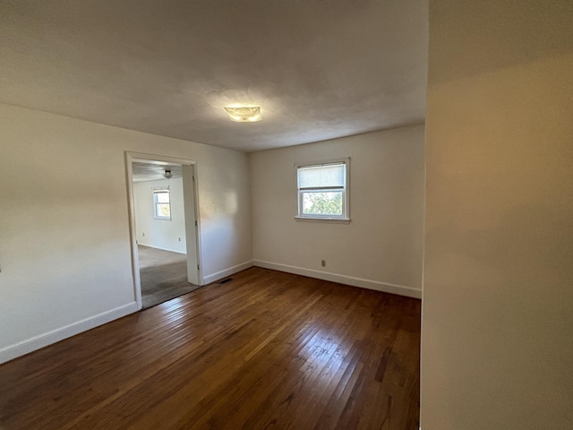 unfurnished room featuring plenty of natural light and dark hardwood / wood-style floors