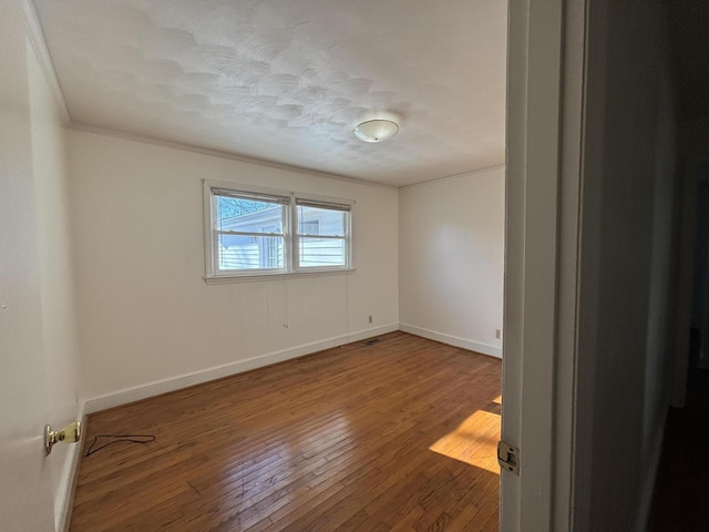 spare room featuring wood-type flooring and crown molding