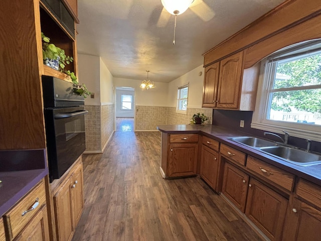 kitchen with black oven, sink, a healthy amount of sunlight, and dark hardwood / wood-style flooring