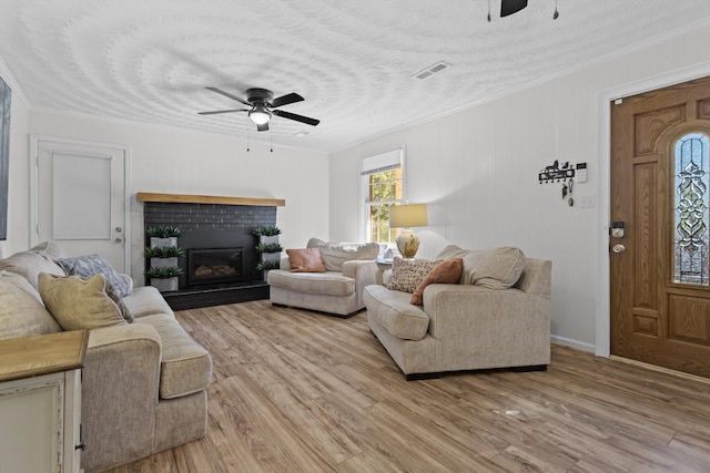 living room with a fireplace, ornamental molding, light hardwood / wood-style flooring, and ceiling fan