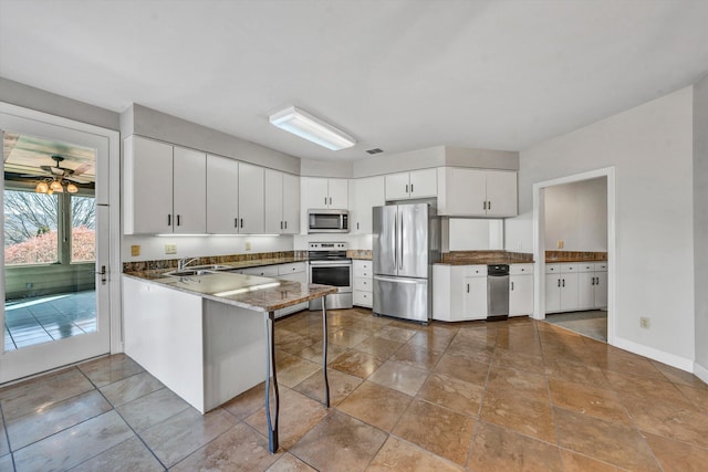 kitchen featuring sink, a breakfast bar area, white cabinetry, kitchen peninsula, and stainless steel appliances