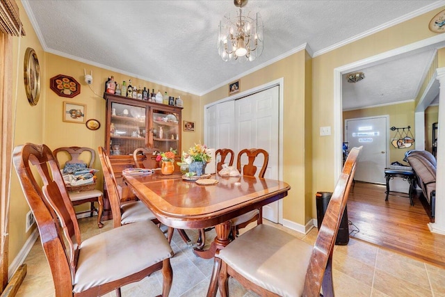 dining room featuring light hardwood / wood-style flooring, a notable chandelier, a textured ceiling, and crown molding