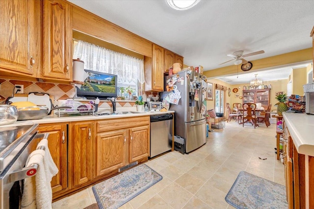 kitchen with stainless steel appliances, tasteful backsplash, ceiling fan with notable chandelier, light tile patterned floors, and pendant lighting