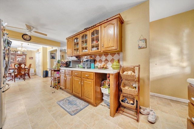 kitchen featuring backsplash, ceiling fan with notable chandelier, light tile patterned flooring, and stainless steel appliances