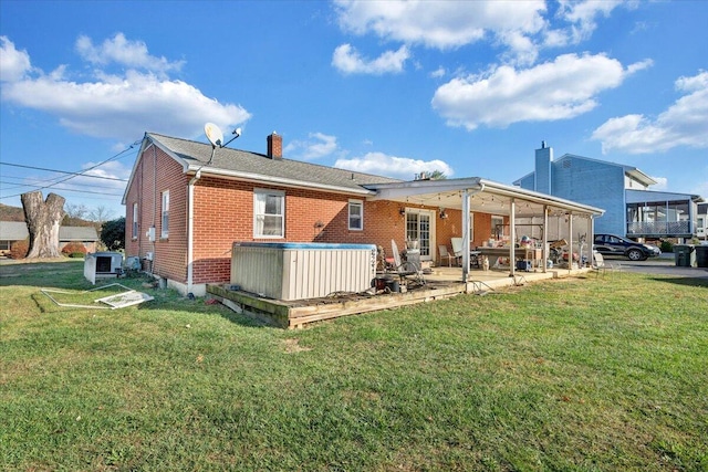 rear view of property featuring a lawn, central AC, a patio, and a hot tub