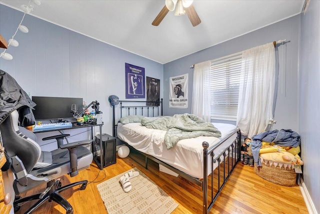 bedroom featuring ceiling fan, wooden walls, and light wood-type flooring