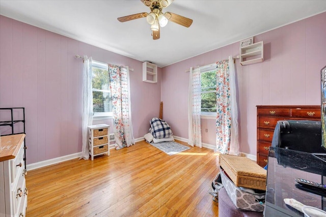 interior space featuring ceiling fan, multiple windows, and light wood-type flooring