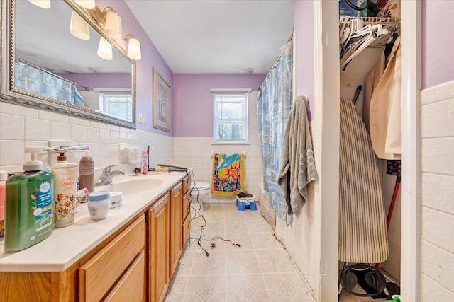 bathroom featuring tile patterned flooring, vanity, toilet, and tile walls