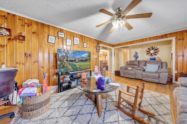 living room featuring a textured ceiling, light hardwood / wood-style flooring, wooden walls, and ceiling fan