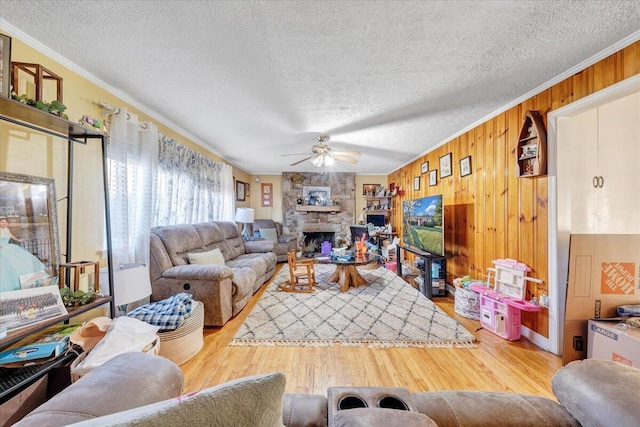 living room featuring ceiling fan, wooden walls, ornamental molding, and light hardwood / wood-style flooring