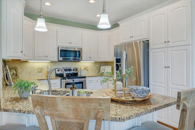 kitchen with appliances with stainless steel finishes, a kitchen breakfast bar, and white cabinetry