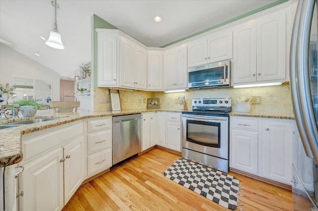 kitchen featuring hanging light fixtures, appliances with stainless steel finishes, light hardwood / wood-style flooring, and white cabinetry