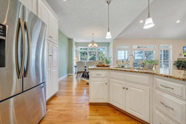 kitchen featuring stainless steel fridge with ice dispenser, a wealth of natural light, white cabinetry, and sink