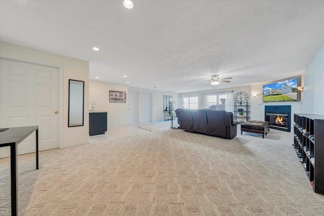 carpeted living room featuring ceiling fan and a textured ceiling