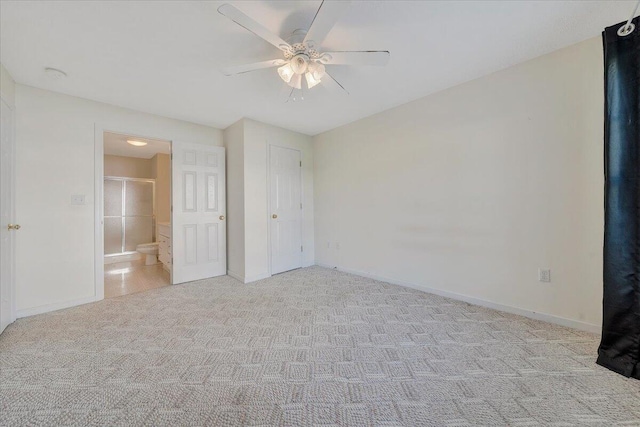 unfurnished bedroom with ceiling fan, light colored carpet, and ensuite bathroom