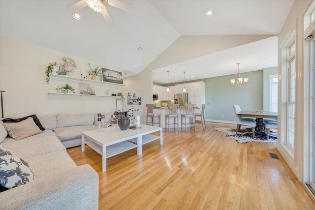 living room featuring ceiling fan with notable chandelier, high vaulted ceiling, and light wood-type flooring