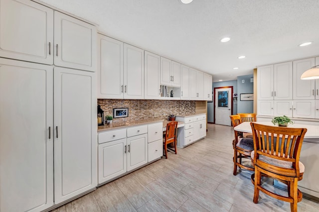 kitchen featuring decorative backsplash, light hardwood / wood-style flooring, white cabinetry, and a textured ceiling