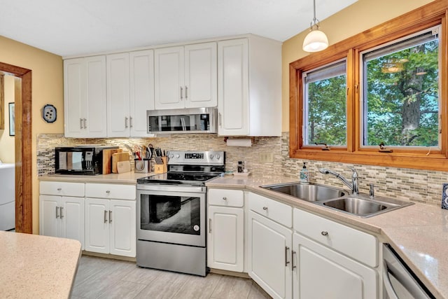 kitchen with appliances with stainless steel finishes, white cabinets, and hanging light fixtures