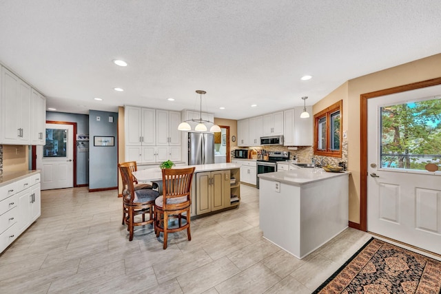 kitchen featuring white cabinetry, decorative light fixtures, stainless steel appliances, and a kitchen island