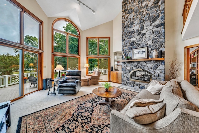 living room featuring track lighting, high vaulted ceiling, carpet flooring, and a fireplace