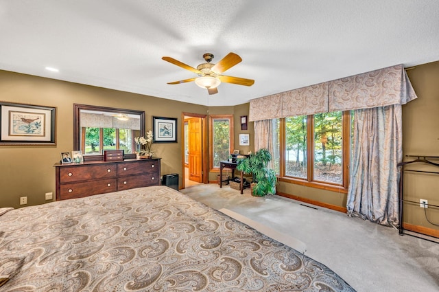 bedroom with ceiling fan, carpet flooring, and a textured ceiling