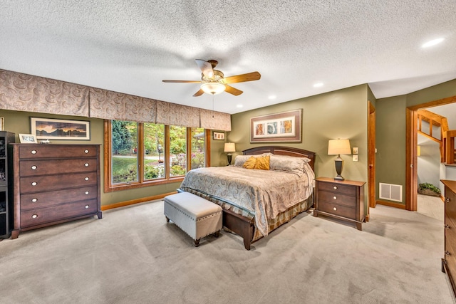 bedroom featuring ceiling fan, light carpet, and a textured ceiling