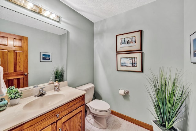 bathroom featuring toilet, a textured ceiling, hardwood / wood-style flooring, and vanity