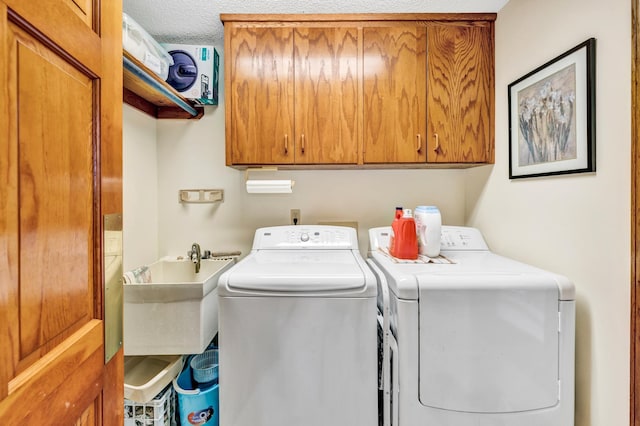 laundry room featuring sink, washer and clothes dryer, a textured ceiling, and cabinets