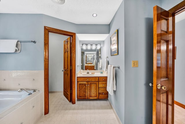 bathroom featuring vanity, a textured ceiling, tile patterned flooring, and tiled bath