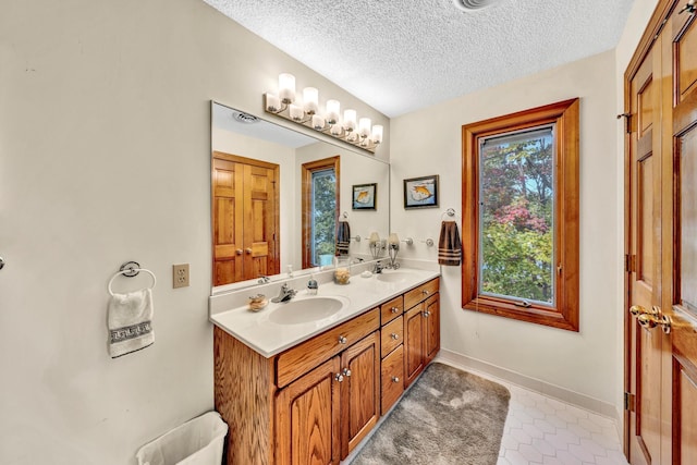 bathroom with vanity, a textured ceiling, and tile patterned flooring