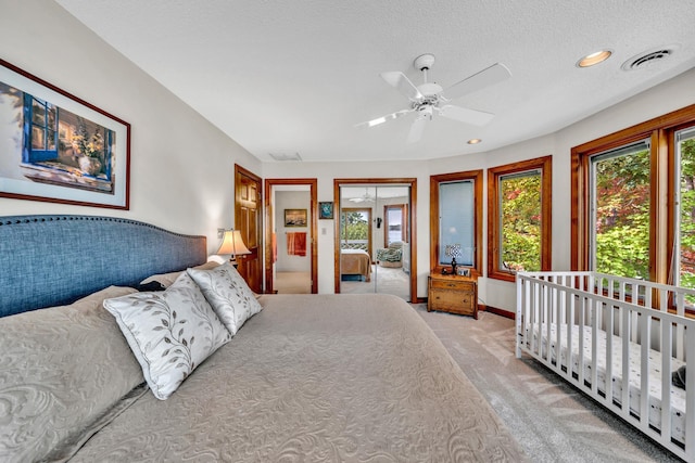 bedroom featuring light carpet, a textured ceiling, and ceiling fan