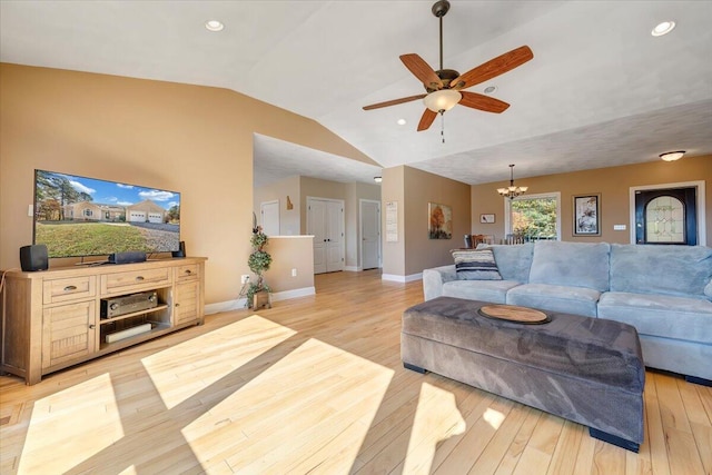 living room featuring ceiling fan with notable chandelier, vaulted ceiling, and light wood-type flooring