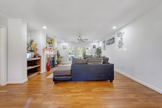 living room featuring a textured ceiling, light hardwood / wood-style floors, and ceiling fan