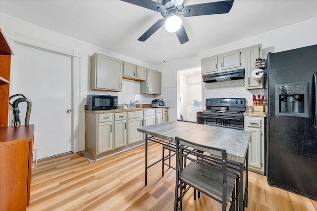 kitchen with black appliances, light wood-type flooring, and decorative backsplash