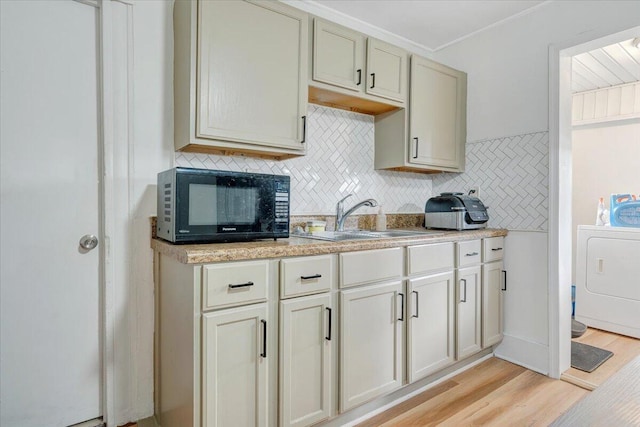 kitchen with sink, backsplash, washer / dryer, and light hardwood / wood-style flooring